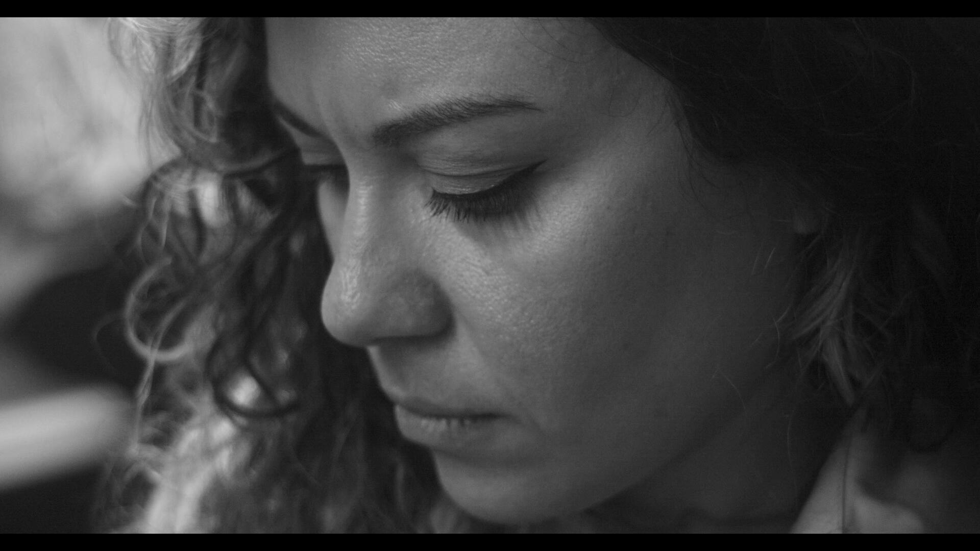 Invited to Leave Still 2 A closeup of Patricia, sitting, looking down, and thinking deeply.