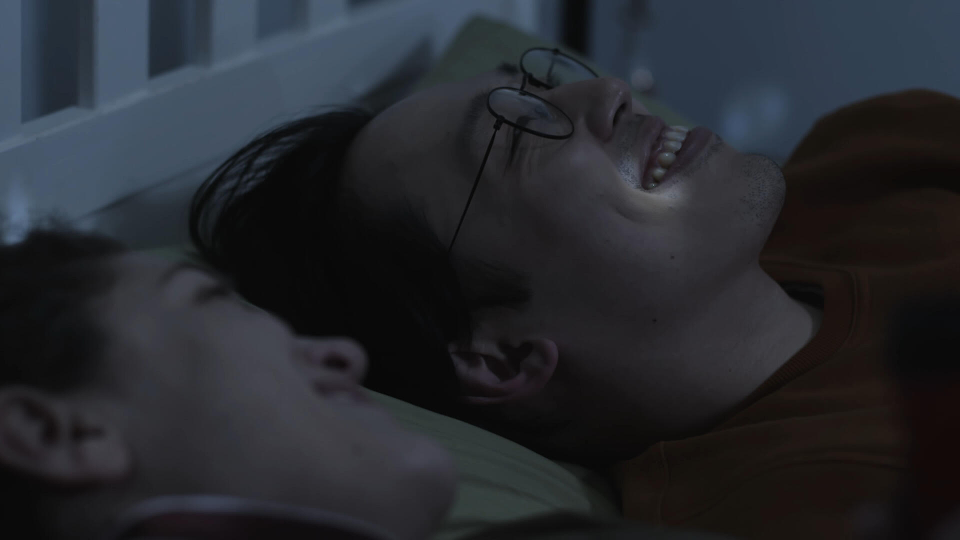 The leading couple lay on a bed, looking up at the ceiling. They laugh; their faces lit by small reflections of light